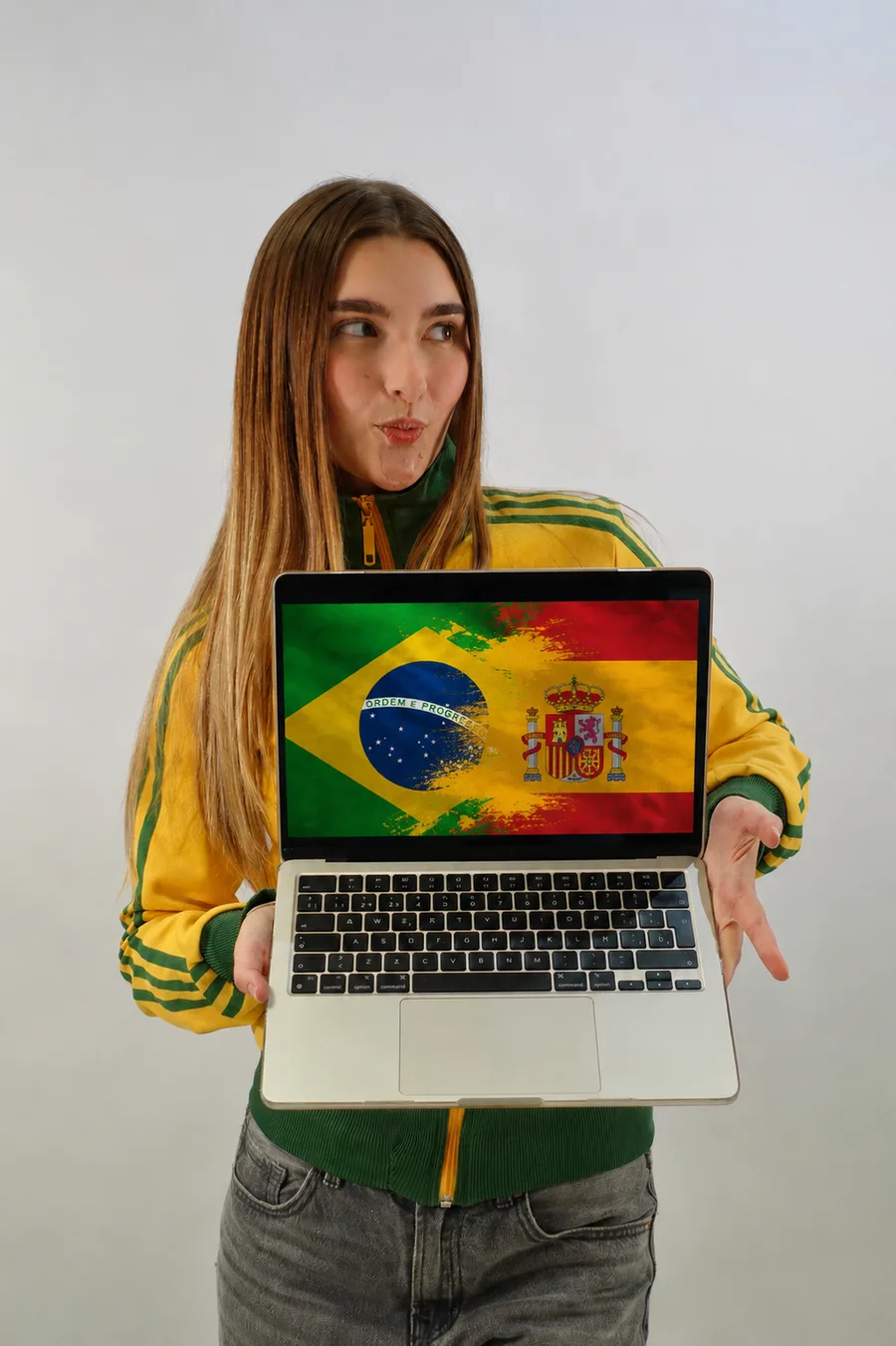 Amanda sorrindo e segurando um notebook com as bandeiras do Brasil e da Espanha na tela